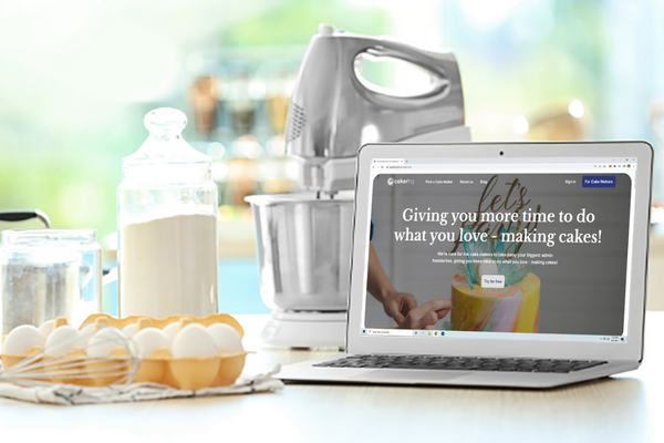Laptop in kitchen on CakerHQ website ready to start baking orders taken with CakerHQ